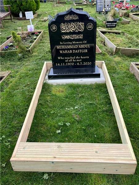Dark headstone with a grass-filled surround