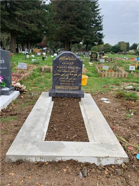 Dark headstone with wide pale kerbs
